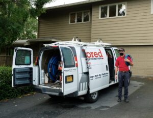 A Taylored Restoration employee with water extraction equipment in a company van in Anchorage, AK