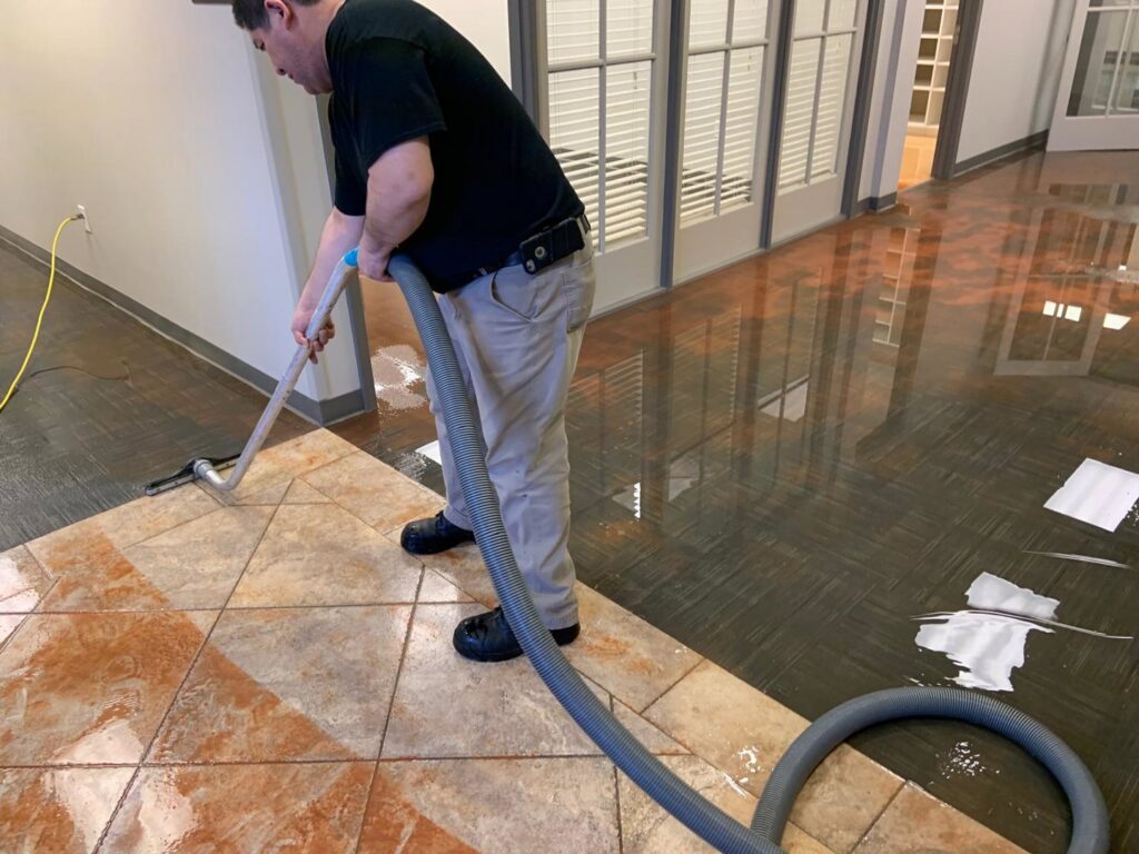 A Servpro technician performing water extraction from a tiled floor during a water damage cleanup in Athens, GA.