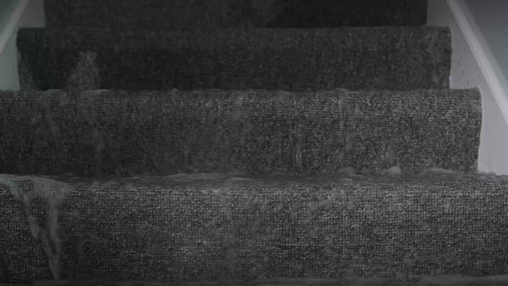 Water flowing down carpeted stairs, indicating severe water damage, in York, PA, handled by 1-800 Water Damage of Harrisburg, PA.