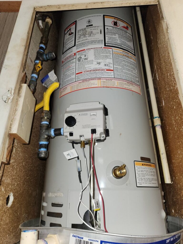 Water damage visible on the floor and wall around a water heater in a closet, addressed by Hull Plumbing, Inc. in Oklahoma City, OK.
