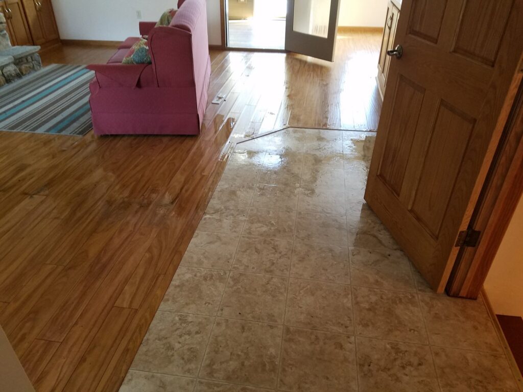Standing water on hardwood and tile floors in a home, indicating water damage, by Elite Restoration LLC in Puyallup, WA.