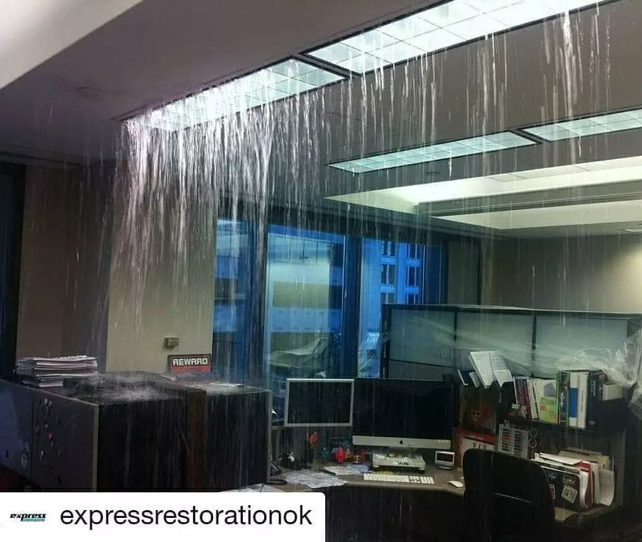 Water pouring from a damaged ceiling in an office, showing a severe water damage issue in Edmond, OK by Express Restoration.
