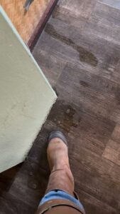 A small puddle of water on a wooden floor indicating a leak, requiring water damage assessment from Rescue One Restoration in Honolulu, HI.