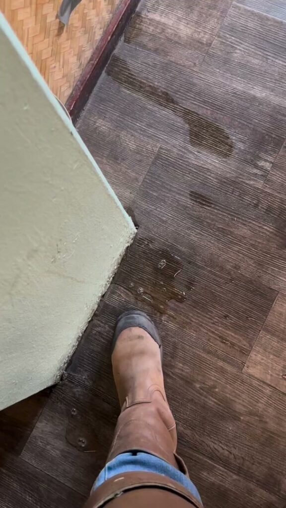 A small puddle of water on a wooden floor indicating a leak, requiring water damage assessment from Rescue One Restoration in Honolulu, HI.