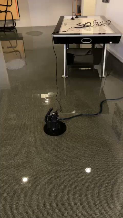 A water pump actively removing standing water from a flooded room during a water damage job by NSH Home Services in Jersey City, NJ.