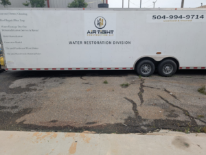 A white trailer for Air Tight Construction's Water Restoration Division, listing services like water damage dry out and mold remediation in Kenner, LA.