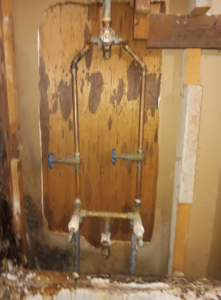 Water-stained plywood and exposed plumbing pipes during water damage repair by Integrity Solutions in Omaha, NE.