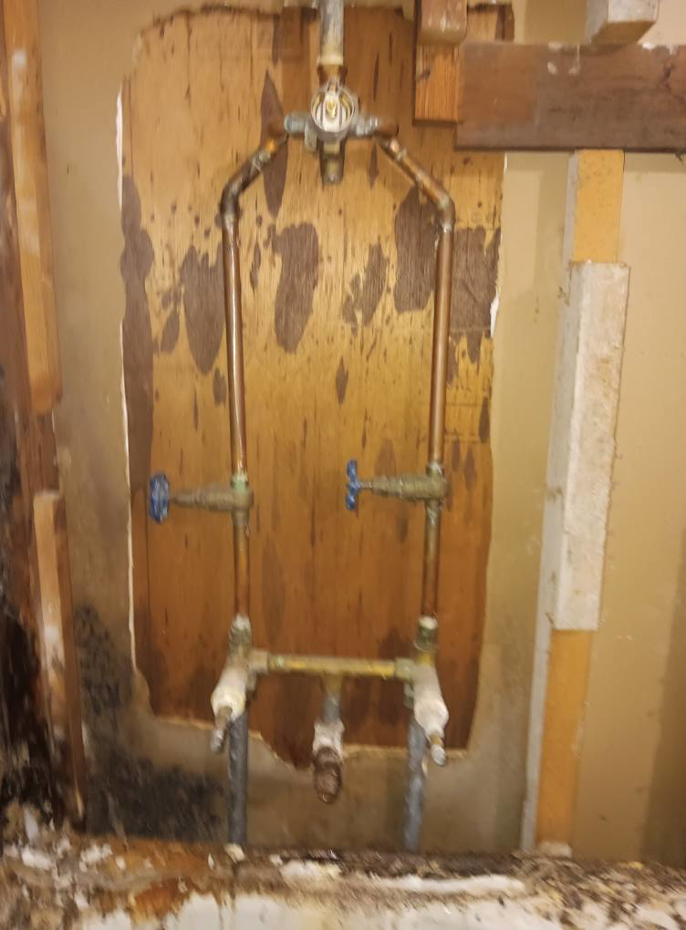 Water-stained plywood and exposed plumbing pipes during water damage repair by Integrity Solutions in Omaha, NE.