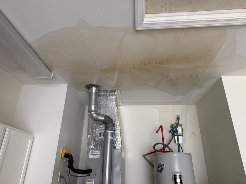 Visible water stains on a ceiling in a garage or utility room, indicating water damage, by PuroClean of Hilton Head in Bluffton, SC.