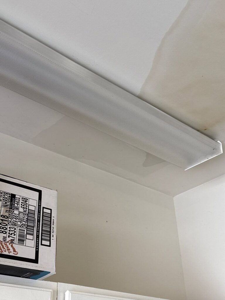 Water stains visible on a ceiling near a fluorescent light fixture, indicating water damage, by PuroClean of Hilton Head in Bluffton, SC.