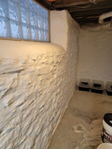 A newly waterproofed basement wall with a glass block window by EFFECTIVE WATERPROOFING in Worcester, MA.