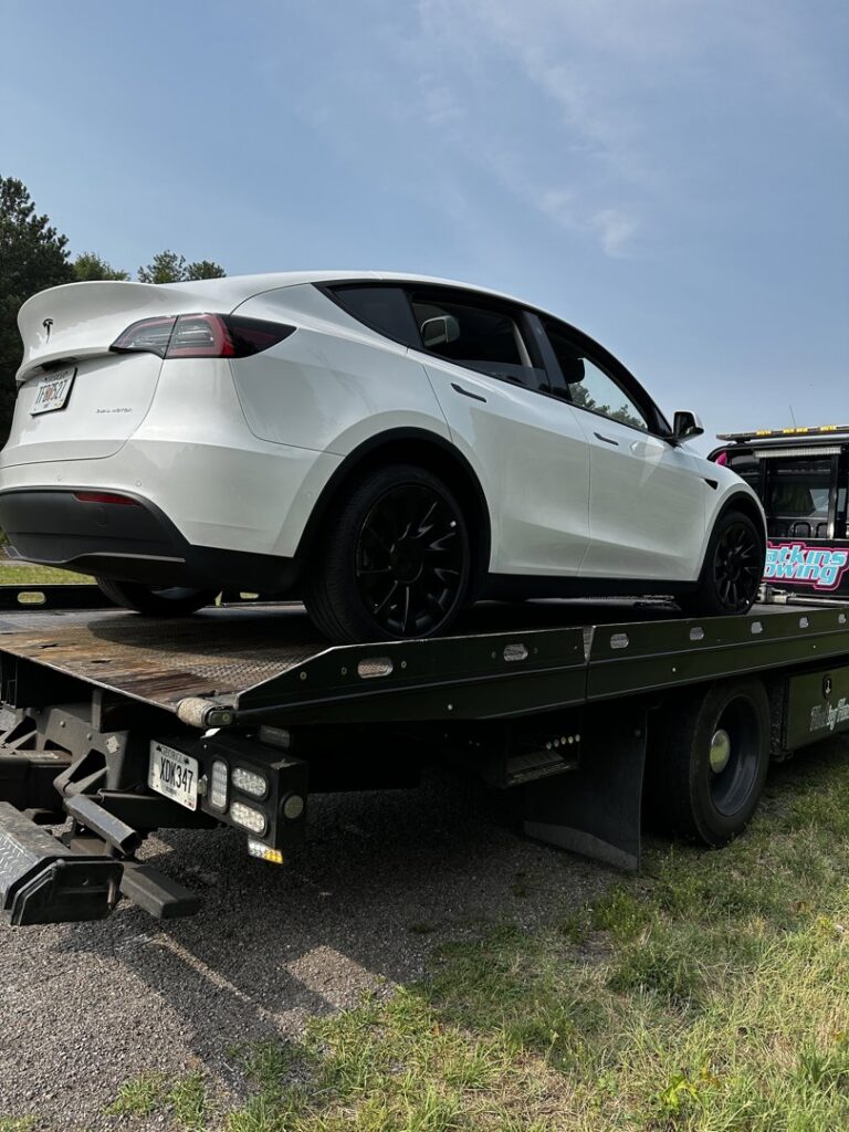 A Watkins Towing flatbed truck transporting a white Tesla Model Y in Augusta, GA.