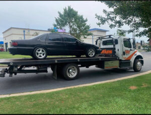 A Watkins Towing flatbed truck transporting a black sedan in Augusta, GA.