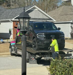 A Watkins Towing truck with a worker loading a dark SUV onto its flatbed in Augusta, GA.