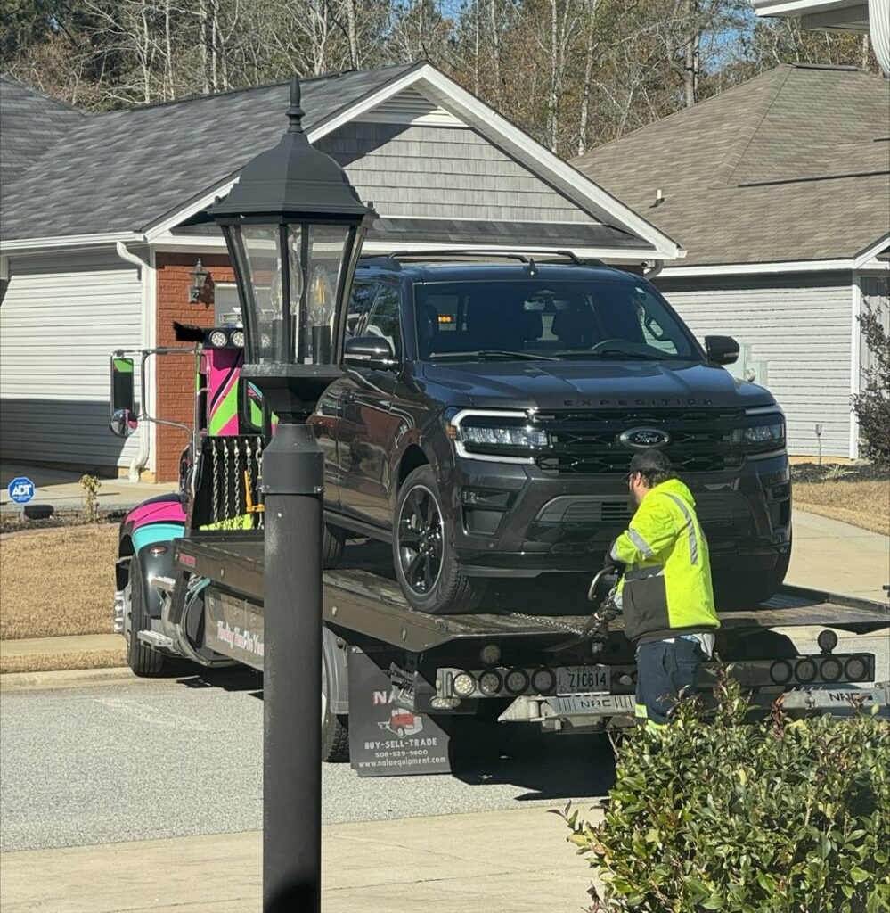 A Watkins Towing truck with a worker loading a dark SUV onto its flatbed in Augusta, GA.