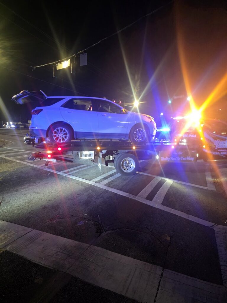 A Watkins Towing truck transporting a white SUV on its flatbed at night in Augusta, GA.