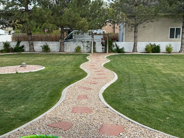 A well-maintained backyard lawn with a decorative gravel path by Lakeside Lawn Care in Sanford, NC.