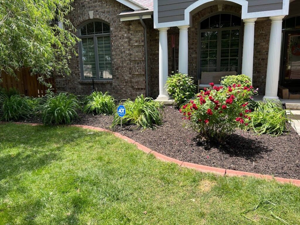A beautifully well-maintained front yard with a neatly mowed lawn and mulched flower beds by Kanger Lawns LLC in Omaha, NE.