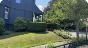 A beautifully maintained lawn and neatly trimmed hedges in front of a house by Steele Lawns in Portland, ME.