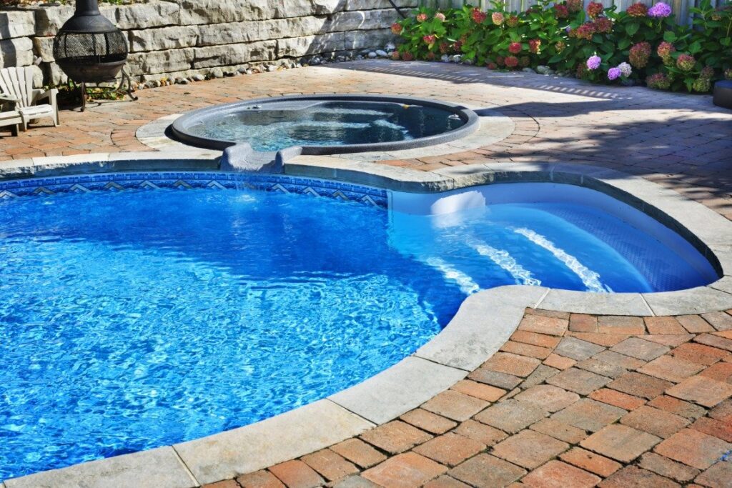 A beautiful, well-maintained pool and spa area with a brick patio, reflecting the quality of service from Pool Tile Cleaning Vegas in Las Vegas, NV.