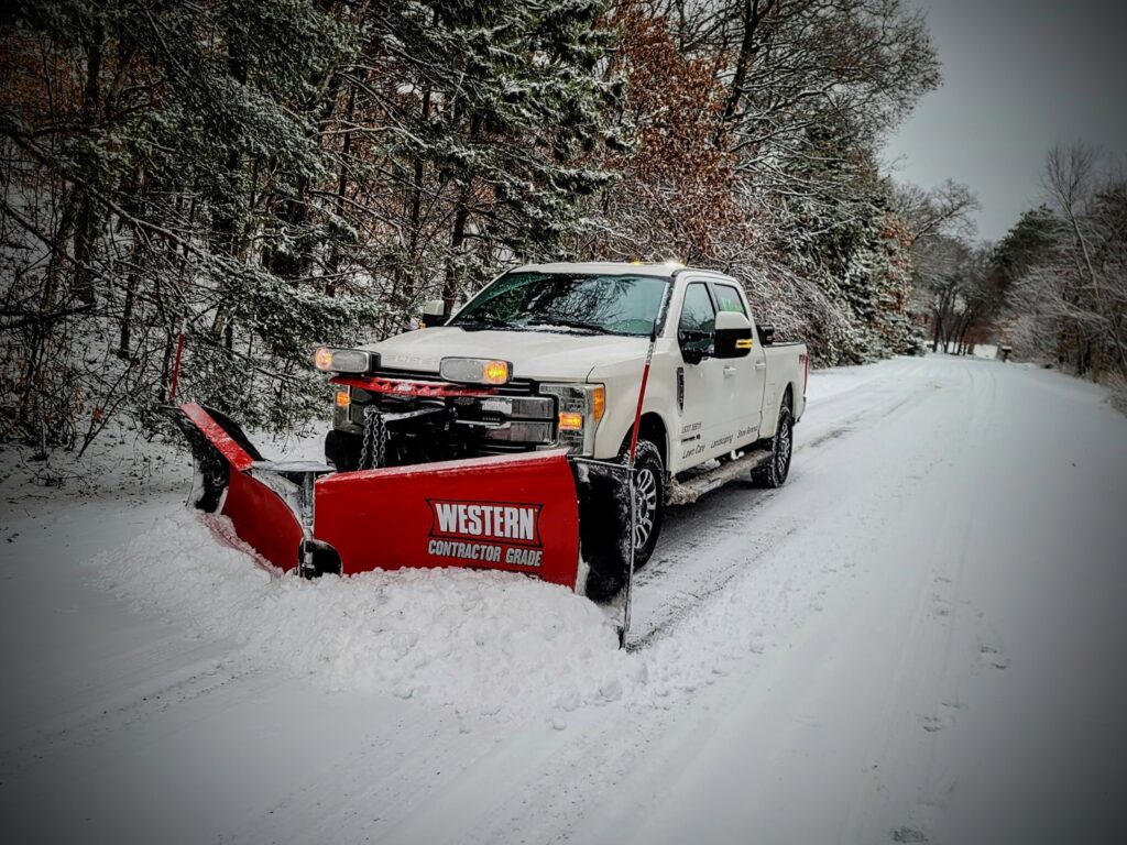 A JD Lawn Care LLC truck with a Western snow plow driving on a snowy road in Berea, OH.