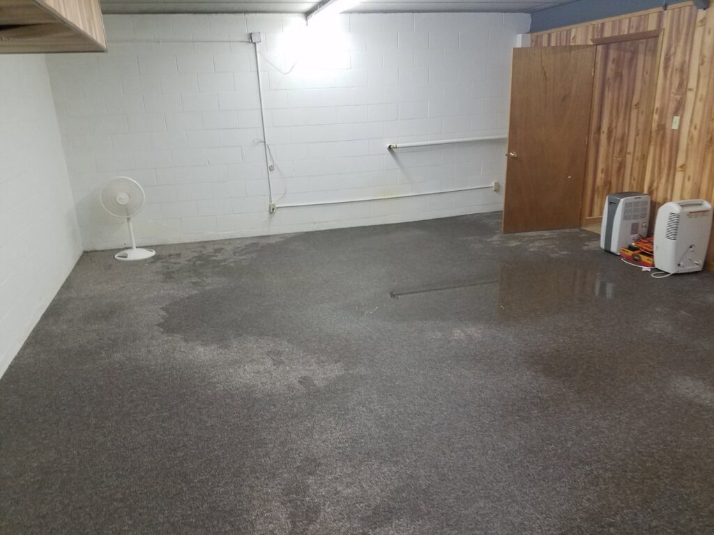 A large room with wet carpet being dried by a fan and dehumidifiers, part of water damage restoration by Elite Restoration LLC in Puyallup, WA.