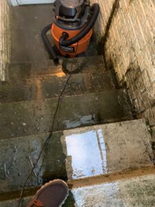 A wet and dirty concrete staircase with a shop-vac, showing a deep cleaning job by Deep Cleaning Service in Frederick, MD.