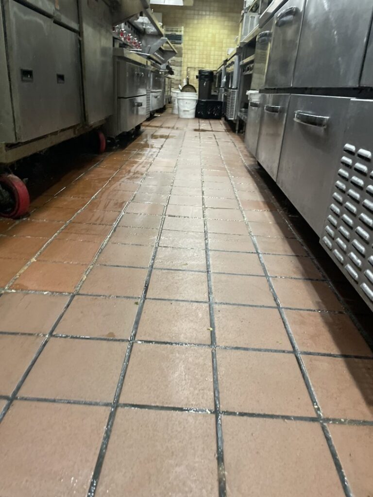 A wet, tiled floor in a commercial kitchen after professional cleaning by Flawless Home & Business Cleaning LLC in Fargo, ND.