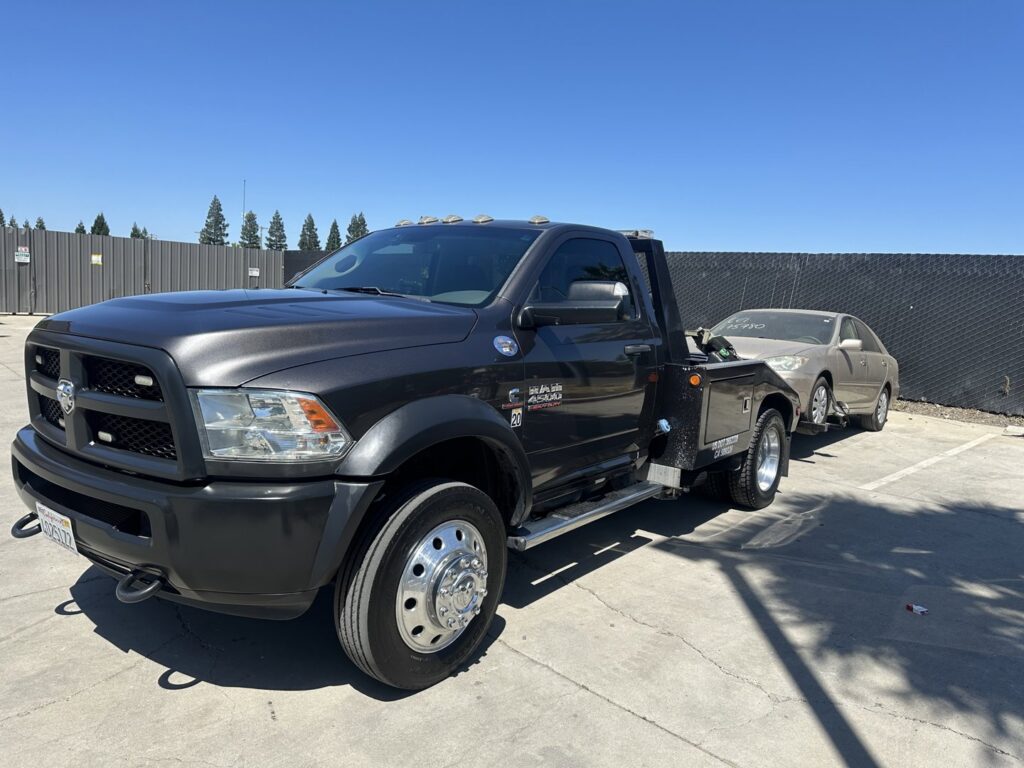 A beige sedan being towed by a wheel lift tow truck by R towing Services in Sacramento, CA.