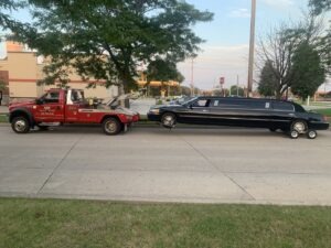 A&W Towing and Repair wheel-lift tow truck towing a black limousine in Appleton, WI.