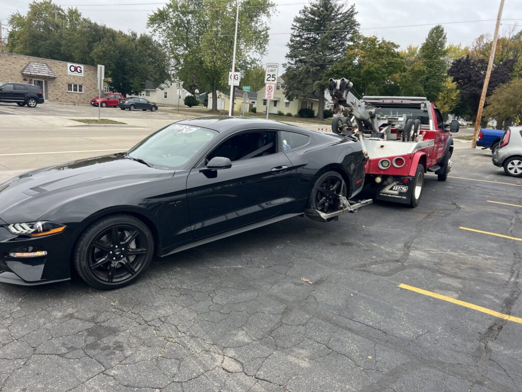 A&W Towing and Repair wheel-lift tow truck towing a black sports car in Appleton, WI.