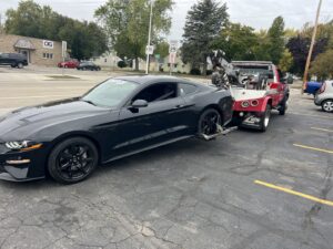 A&W Towing and Repair wheel-lift tow truck towing a black sports car in Appleton, WI.