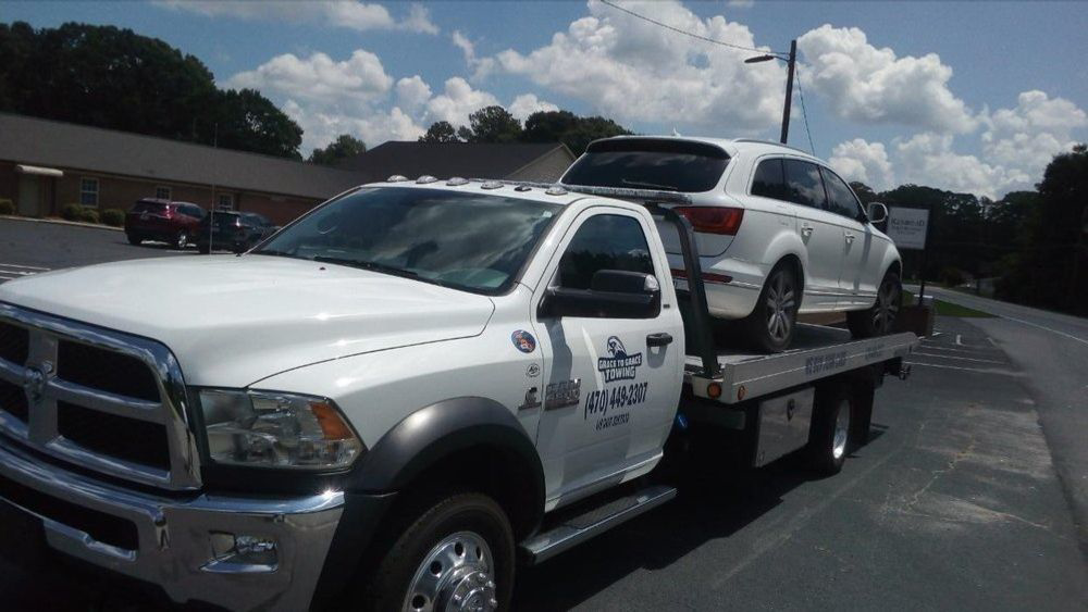 A white Audi SUV being transported on a flatbed tow truck by Grace to Grace Towing in Atlanta, GA.