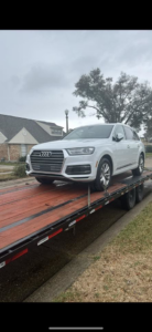 A white Audi SUV being transported on a flatbed trailer by 82Hauling & More LLC in St. Louis, MO