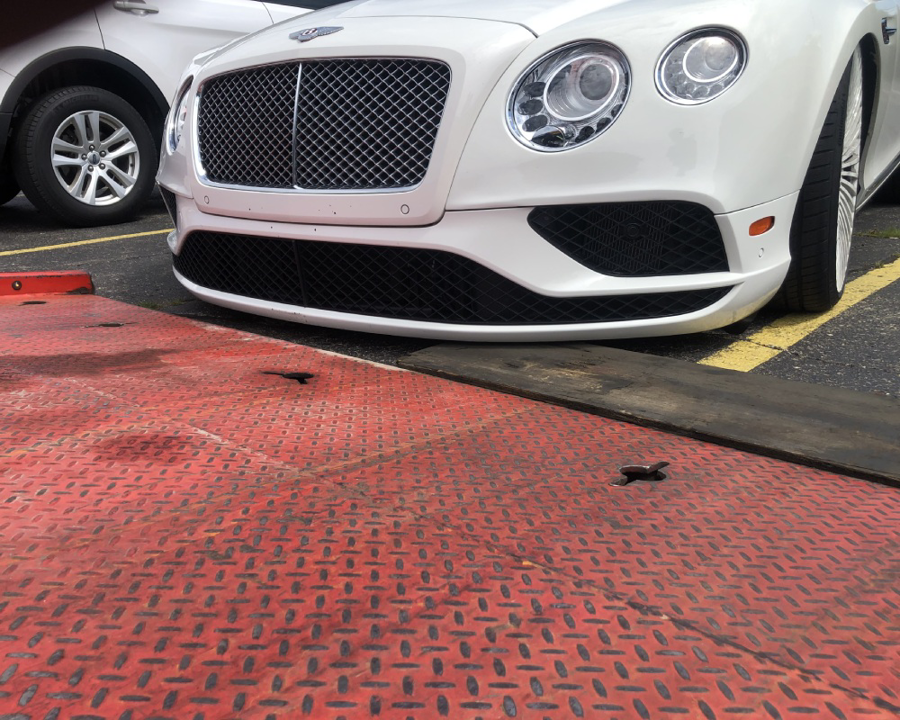 The front of a white Bentley car being transported on a flatbed tow truck by Triple D's Towing in Sterling Heights, MI.