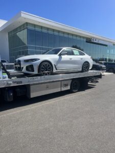 A white BMW sedan being transported on a flatbed tow truck by 101 auto towing inc in San Jose, CA.