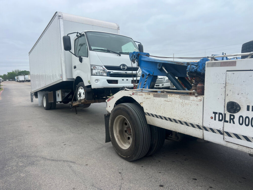 A white box truck being towed by a heavy-duty tow truck from 247 Towing in San Antonio, TX.