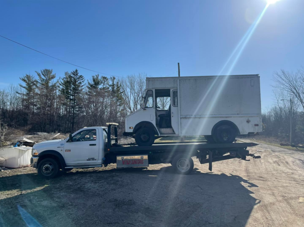A white box truck being transported on a flatbed tow truck by Demand Salvage & Towing in Kenosha, WI.