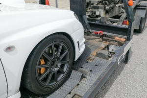 A white car being towed on a flatbed truck by Buckeye Riverside Towing in Cincinnati, OH.
