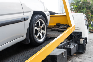 A white car being loaded onto a yellow flatbed tow truck by DunRite Towing Jonesboro in Jonesboro, AR.