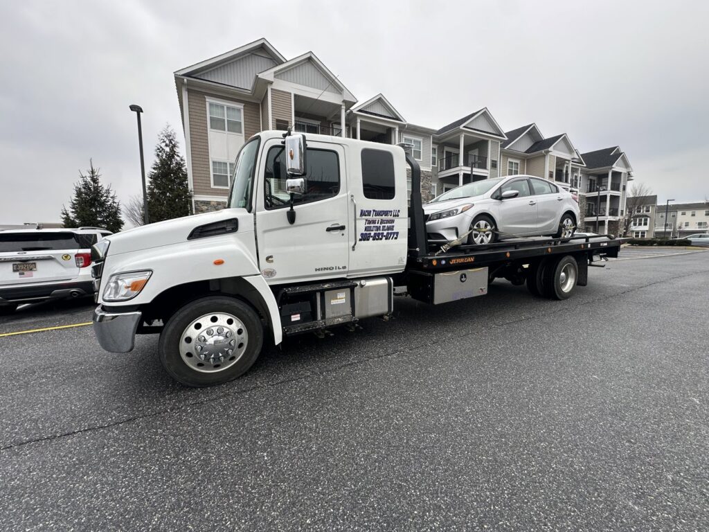 A white car loaded onto a flatbed tow truck from Nacho Transports llc in Middletown, DE.