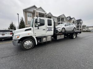 A white car loaded onto a flatbed tow truck from Nacho Transports llc in Middletown, DE.