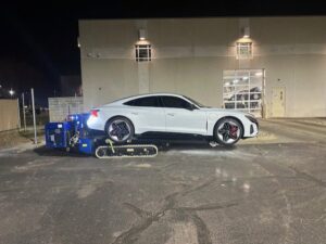 A white car being towed with specialized low-clearance equipment at night by Jim & Ron's Service Inc. in Sioux Falls, SD.