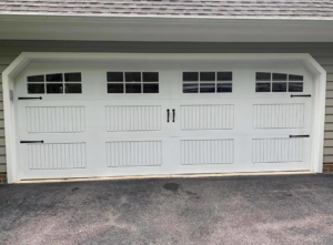 A white carriage-style garage door with decorative hardware and windows by Next Level Garage Doors in Locust Grove, GA.