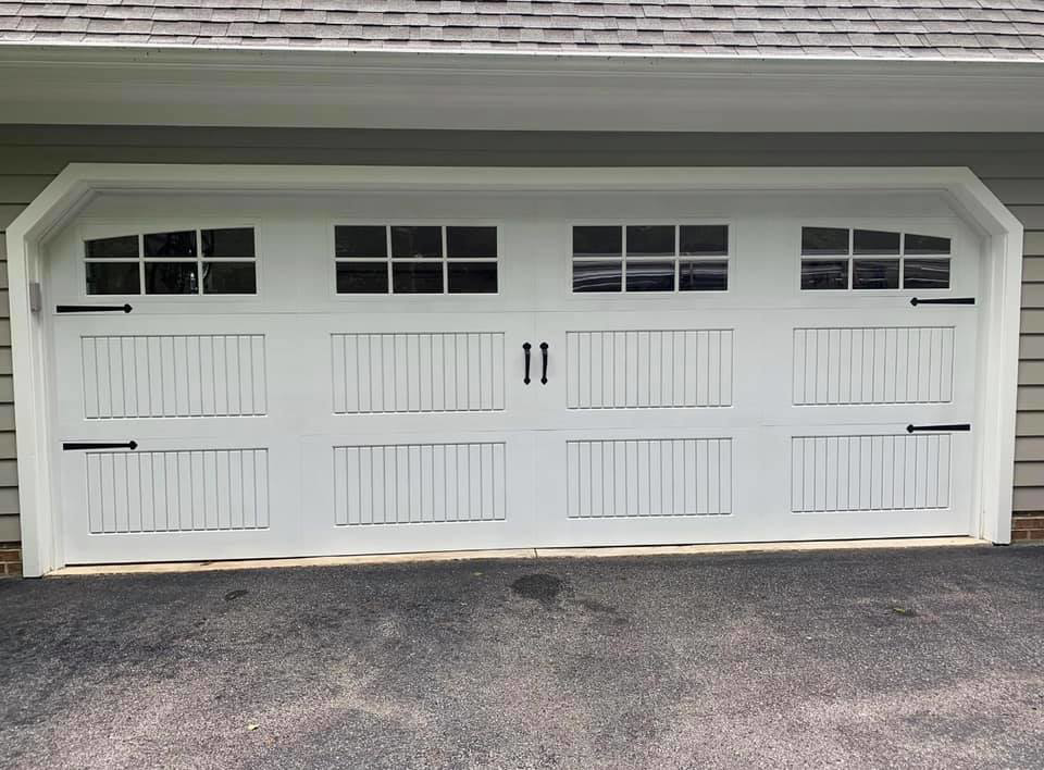A white carriage-style garage door with decorative hardware and windows by Next Level Garage Doors in Locust Grove, GA.