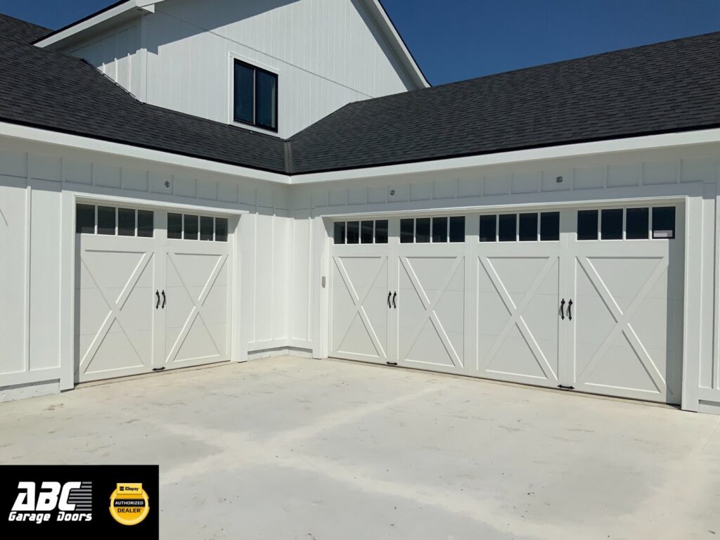 Two white carriage-style garage doors with multiple windows installed by ABC Garage Doors KC in Kansas City, KS.
