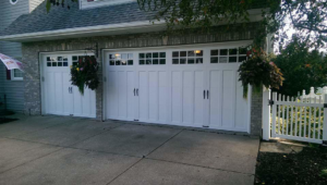 Installation of two white carriage-style garage doors on a home by 74 Garage Door Company in Lake Park, FL