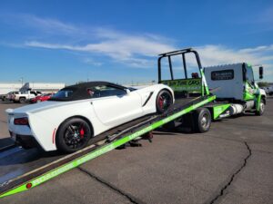 A white convertible sports car being transported on a flatbed tow truck by Caliber Towing in Phoenix, AZ.