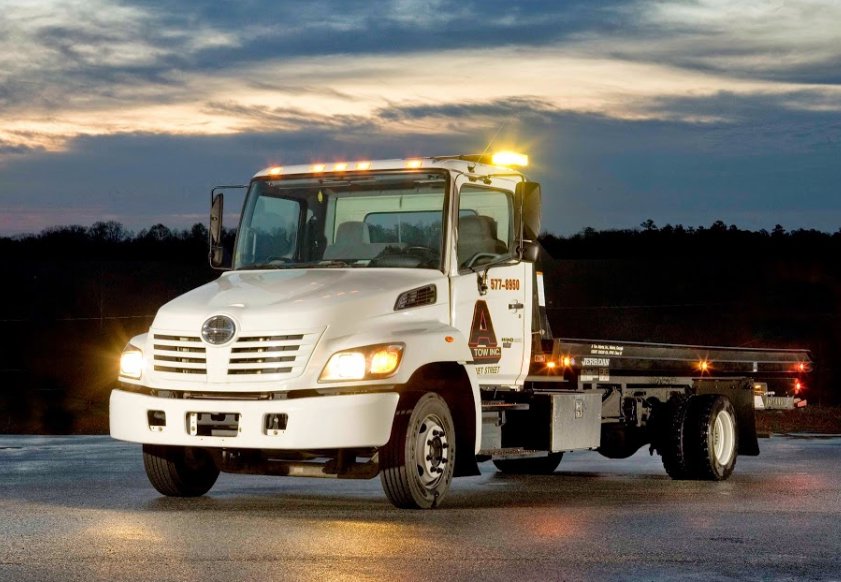 A white flatbed tow truck from A-Tow Atlanta / Alpharetta with branding on the side, ready for service in Atlanta, GA.