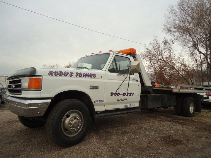 A white flatbed tow truck from Robo's Towing in Marriott-Slaterville, UT, parked and ready for a tow.
